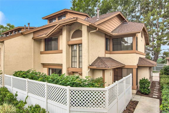 Front view of a two-story house with a sloped roof and a small fenced yard.