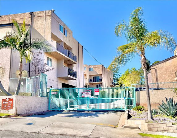 Front view of a multi-story apartment building with gated entrance.