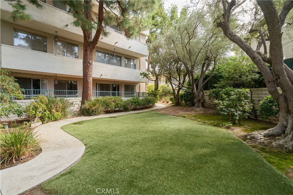 Side view of a multi-story building with a garden path and trees.