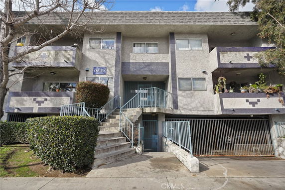Front view of a three-story apartment building with balconies and a gated entrance.