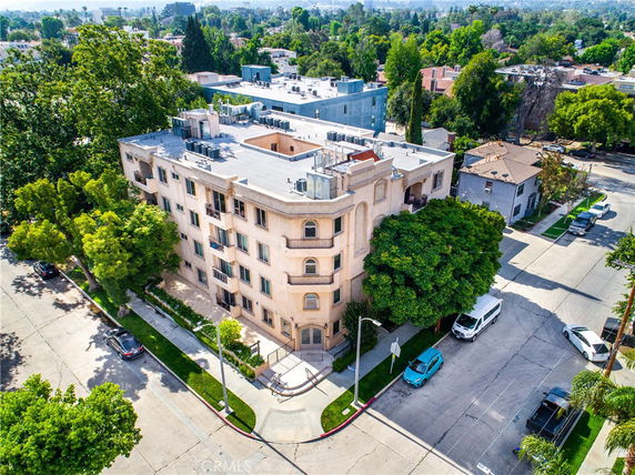 Aerial view of a multi-story building in a residential area with trees and roads.