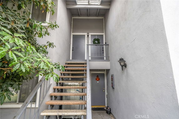 Front view of a building entrance with stairs leading to a second-floor doorway.