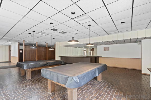 Room with billiard tables under suspended lights.