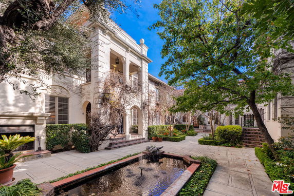 Front view of a multi-story house with arched windows and a patio area.