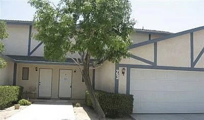 Front view of a house with a garage and a small tree in front.