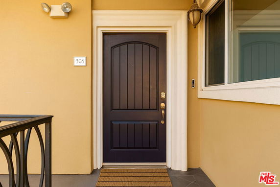 Front view of a building entrance with a dark wooden door and adjacent window.