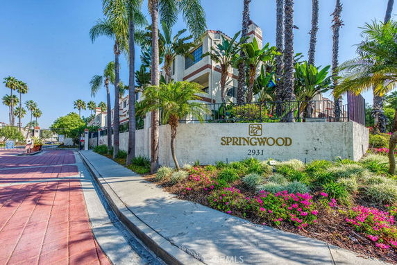 Front view of a residential building with palm trees and a sign reading 'Springwood 2931'.