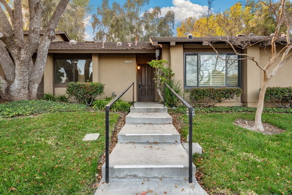 Front view of a single-story house with a walkway and railing leading to the entrance.
