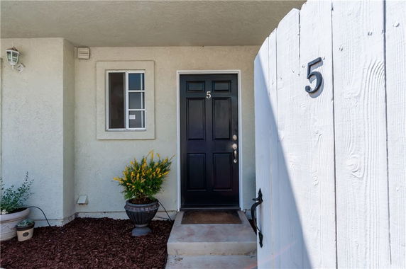 Front view of a house with a black door and white fence, marked with the number 5.