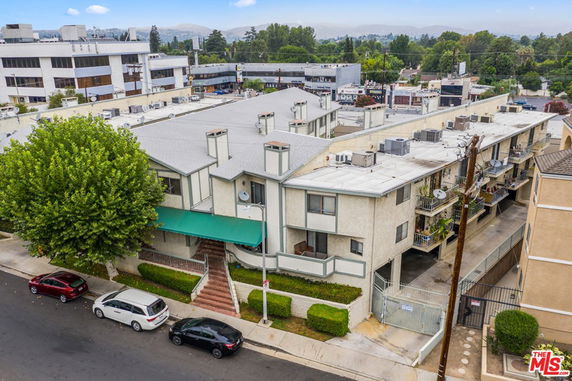 Aerial view of a multi-story apartment building with a gated entrance and individual balconies.