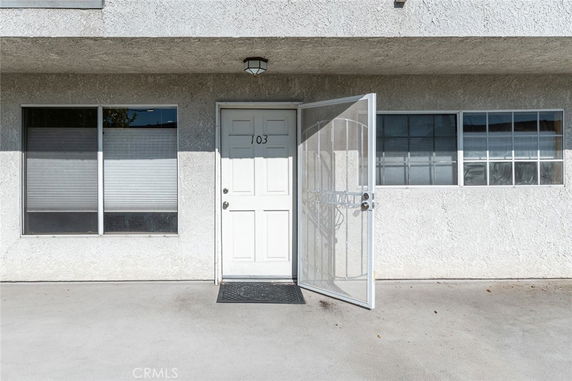 Front view of a building entrance with a white door and two windows.