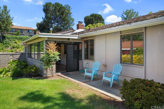 Front view of a single-story house with a patio and chairs.