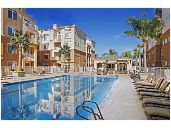 Outdoor swimming pool area with apartment buildings in the background.