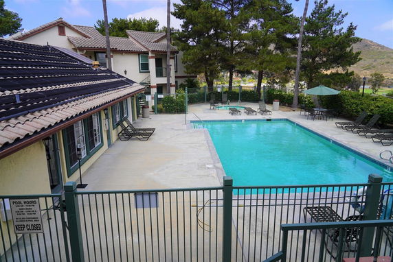 Outdoor swimming pool area with surrounding lounge chairs and umbrellas.