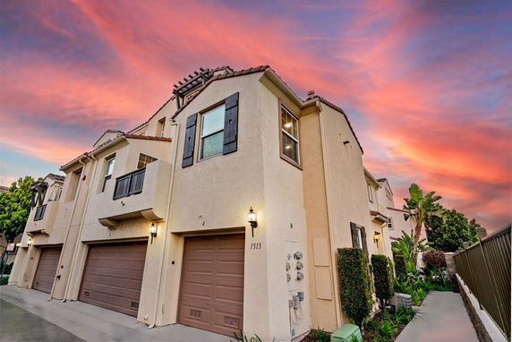 Front view of a multi-story house with attached garages under a colorful sky.