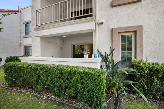 Front view of a two-story building with balconies and a garden area.