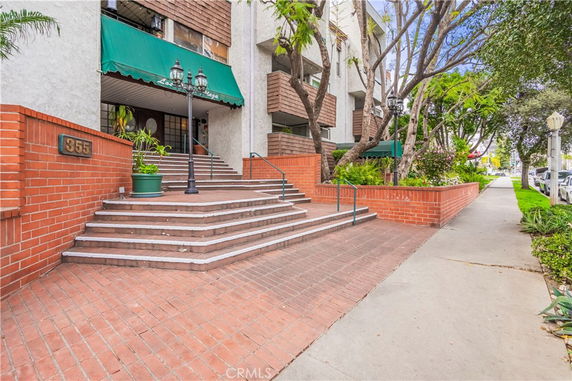 Front view of a multi-story building with red brick steps and green awnings.