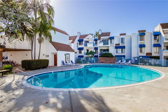 View of an outdoor swimming pool in a residential complex with surrounding buildings.