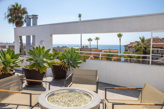 Rooftop with seating area and plants overlooking the ocean.