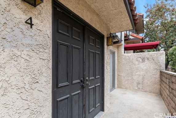 Front view of a house with a beige textured facade and a double black door.
