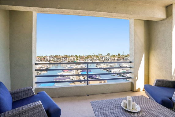 Balcony view overlooking a marina with boats and houses in the background.