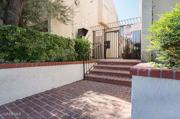 Entrance view of a building with brick steps leading to a gated entry.