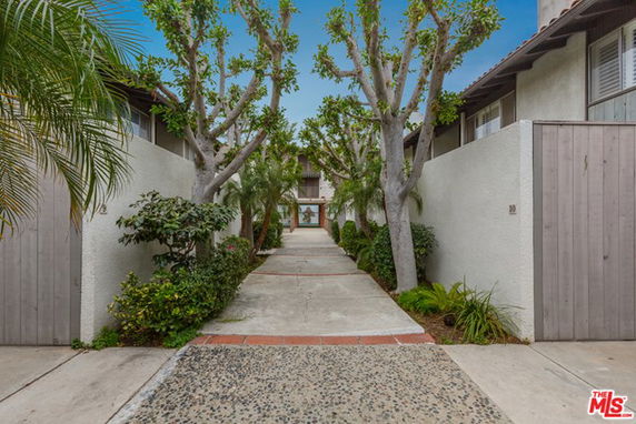 Front view of a building entrance with a pathway and surrounding trees.