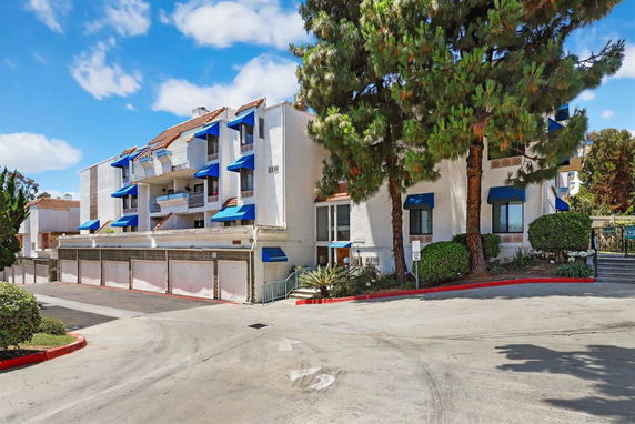 Front view of a multi-story residential building with blue awnings.