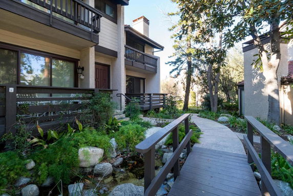 Front view of a multi-story house with balconies and a walkway bridge.