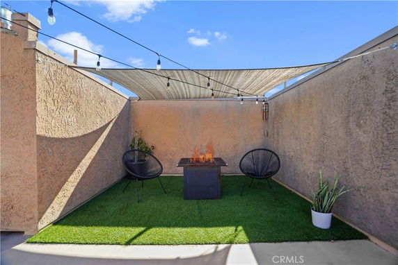 Rooftop seating area with artificial grass, two chairs, and a fire pit.