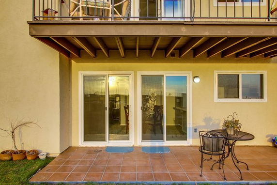 View of a house exterior with a balcony and patio area.