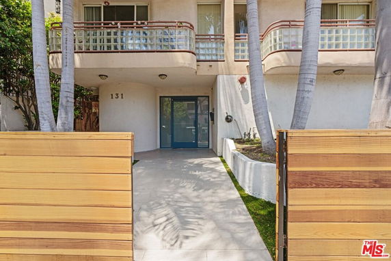 Front view of a building with a wooden fence and entrance walkway.