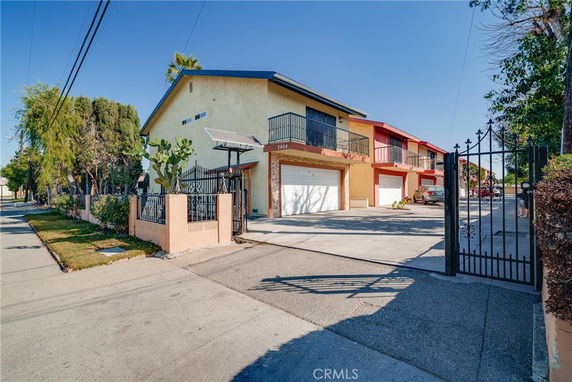 Front view of a two-story residential building with a gated entrance and attached garages.