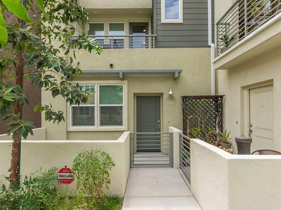Front view of a multi-story townhouse with a small entryway and balcony.