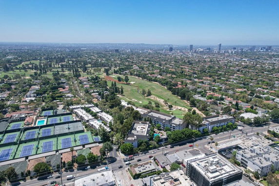 Panoramic view of a cityscape with buildings, tennis courts, and a golf course.