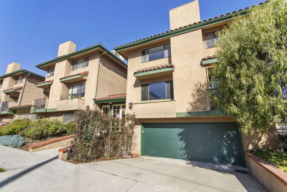 Front view of a multi-story townhouse with a green garage door.
