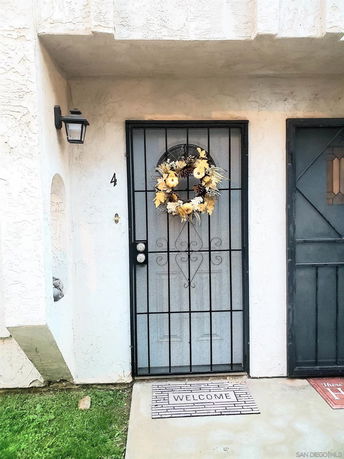 Front view of a house entrance with a decorative wreath and welcome mat.