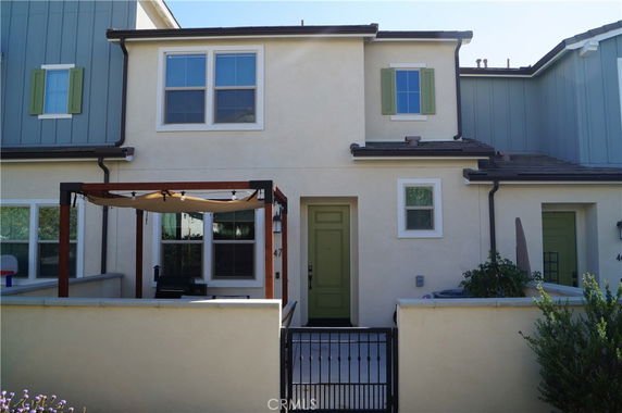 Front view of a two-story house with a gated entrance and pergola.