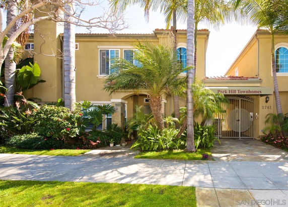 Front view of Park Hill Townhomes, a two-story building with a gated entrance and palm trees in the foreground.