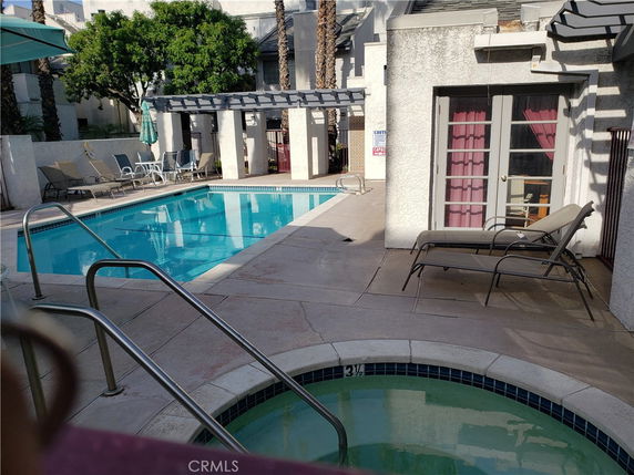 Outdoor swimming pool with lounge chairs and a small hot tub.