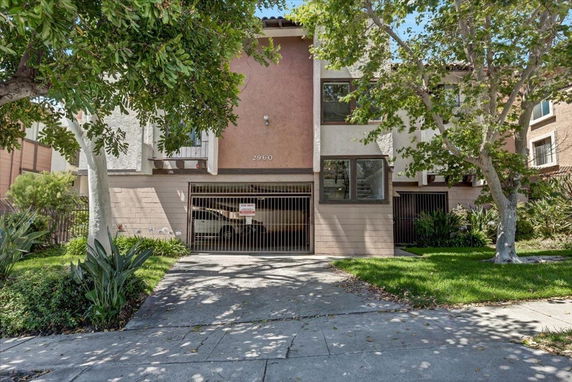 Front view of a residential building with two floors and gated parking area.