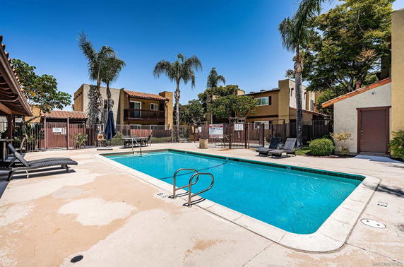 Outdoor swimming pool area with sun loungers and surrounding residential buildings.