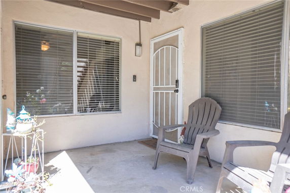 Patio area of a house with two windows and a door, featuring two chairs.