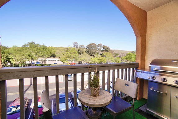 View from a balcony showing trees and a parking area below.