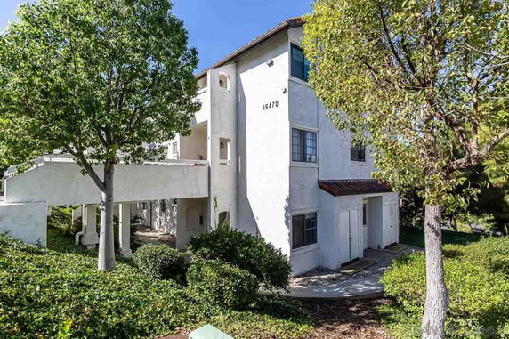Front view of a multi-story white apartment building with an outdoor staircase.