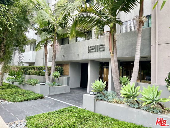 Front view of a building with a modern facade and landscaped entrance.