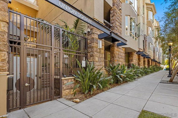 Front view of a multi-story building with stone facade and gated entrance.