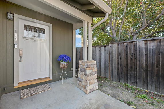 Front view of a house entrance with a white door and wooden fence.