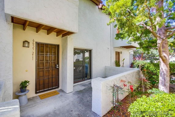 Front view of a two-story house entrance with a wooden door and a sliding glass window.