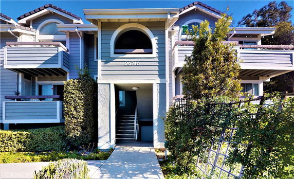 Front view of a multi-story residential building with balconies and an arched window.